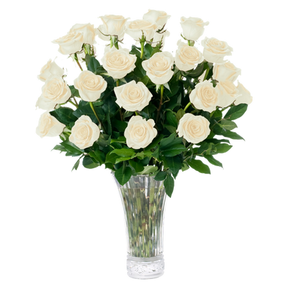 A bouquet of 20 fresh white roses with green leaves arranged in a clear glass vase, isolated on a white background.